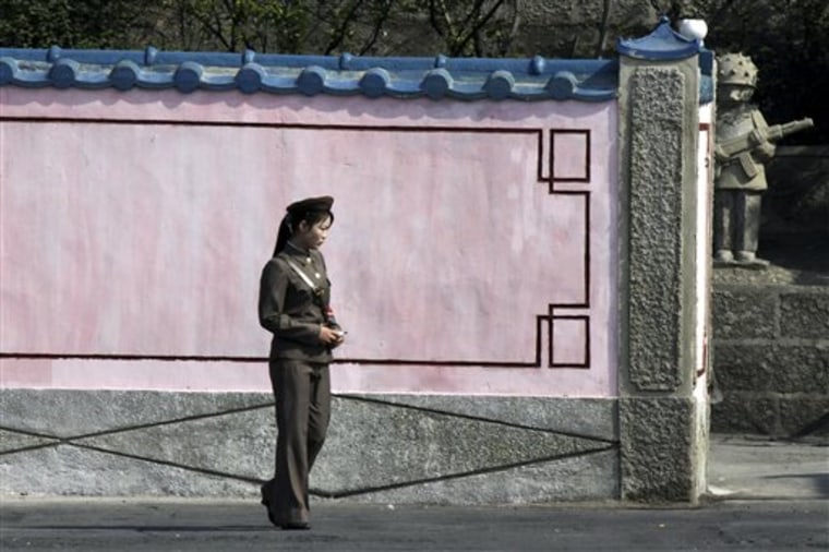 A female North Korean soldier walks along a wall to a compound in North Korea's Sinuiju seen from a boat along the Yalu river near the Chinese border town of Dandong in China's northeastern Liaoning province, on May 23.